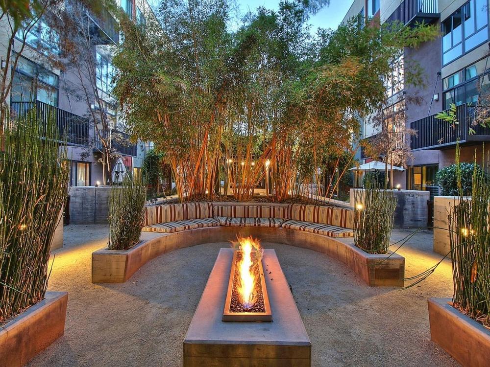 Fire pit court at dusk, ringed by curved bench seating and bamboo
